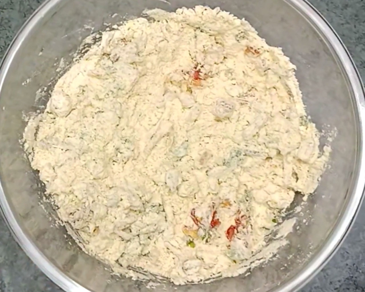 Mixing gram flour with vegetables to make chilla batter