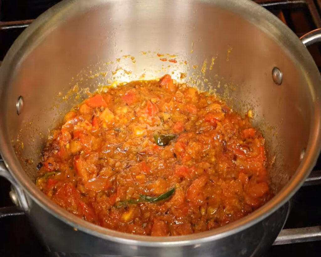 Cooking tomatoes with spices to prepare masala gravy for cauliflower curry