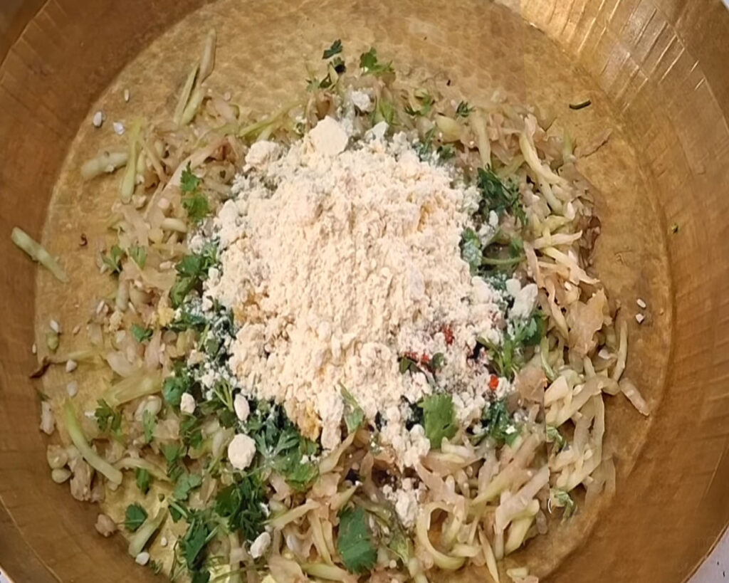 Mixing grated bottle gourd with besan and spices to make lauki kofta dough