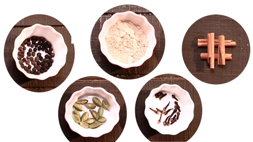 Masala Chai ingredients including tea leaves, ginger, cardamom, cinnamon, cloves, black pepper, and milk arranged on a wooden board