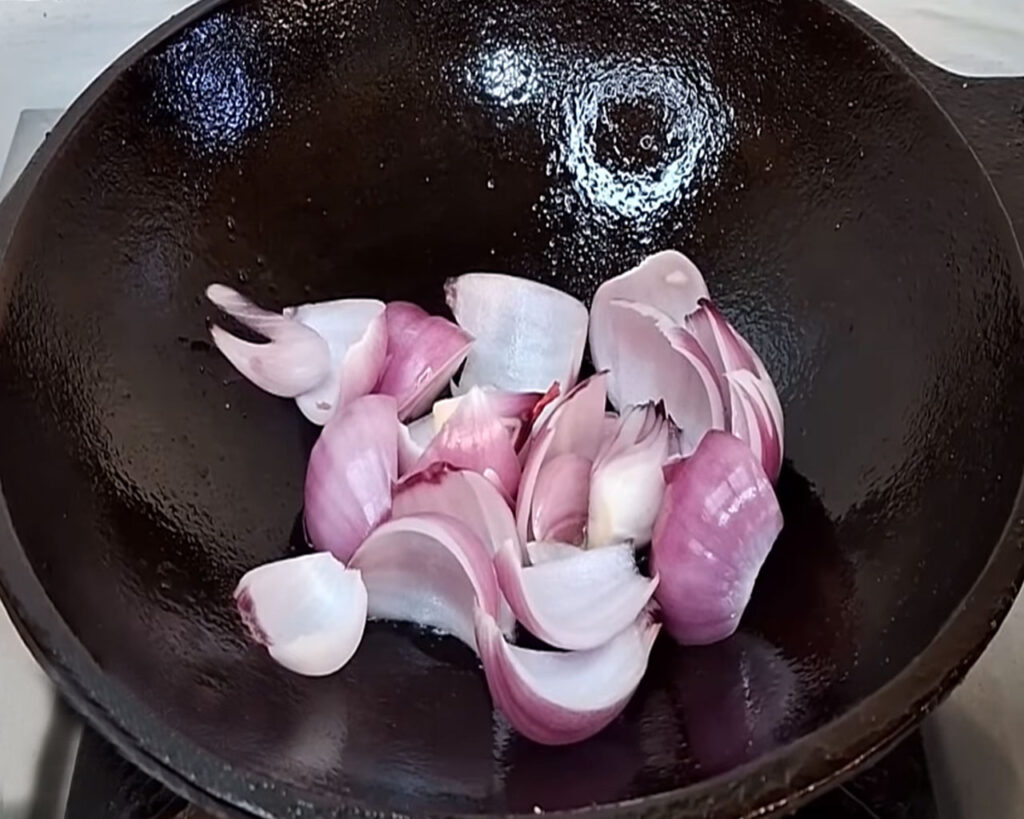 Chopped onions sautéing in mustard oil until golden brown for curry base