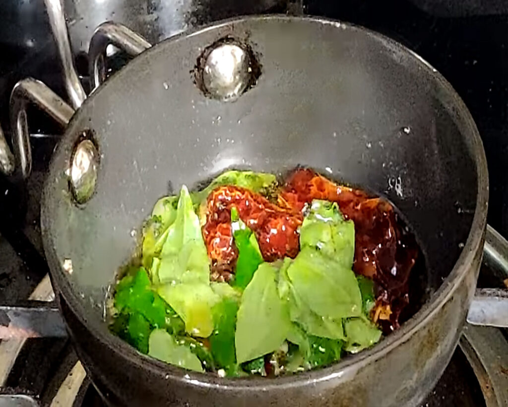Tadka being prepared with mustard seeds, urad dal, dried red chilies, curry leaves, and asafoetida in mustard oil