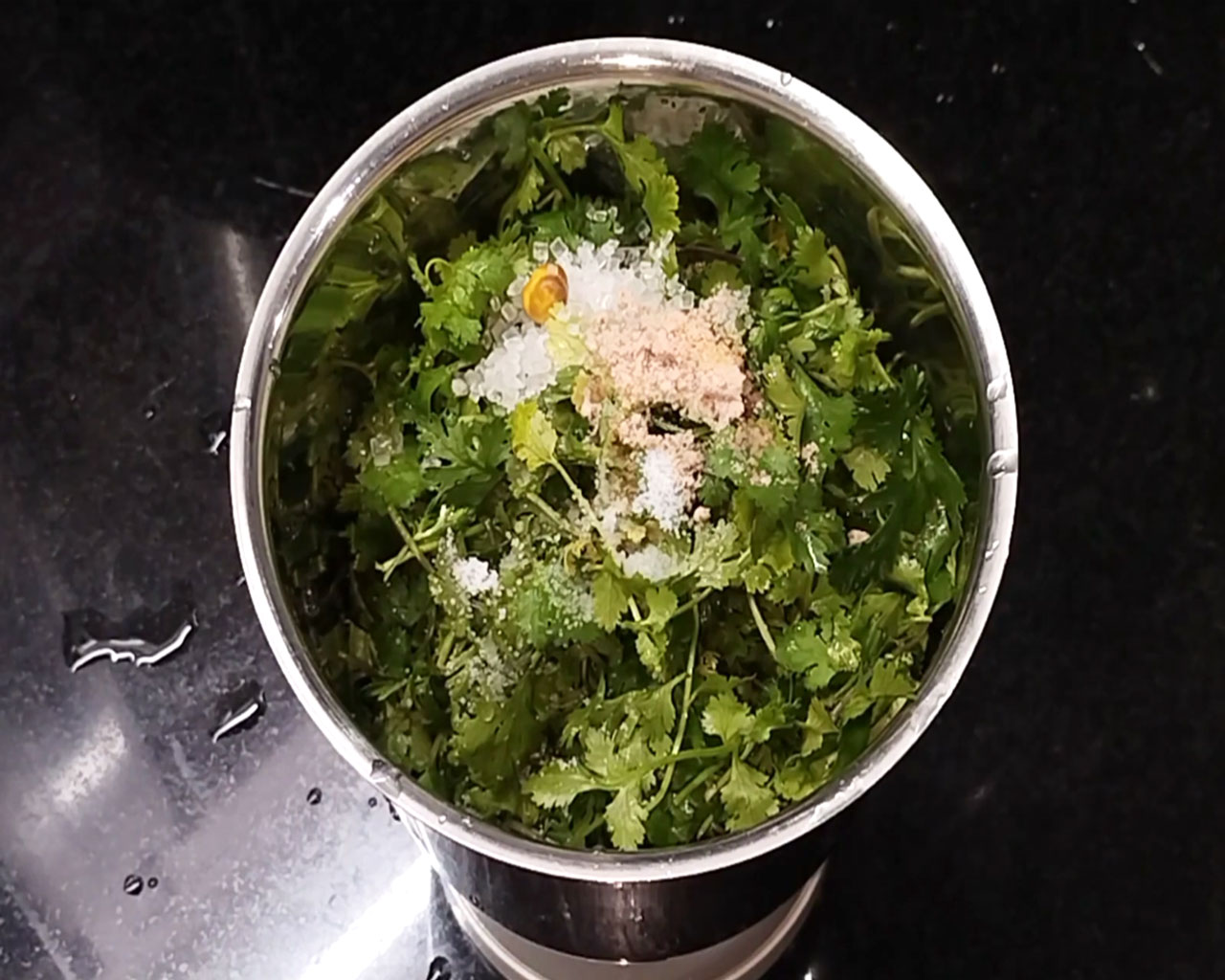 Adding sugar, salt, and water to make coriander chutney