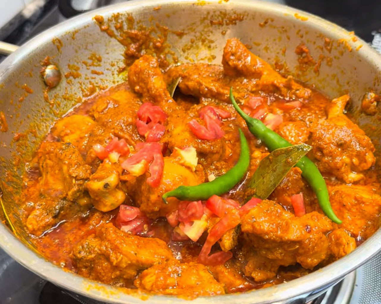 Chopped tomatoes and green chilies added to Indian chicken curry