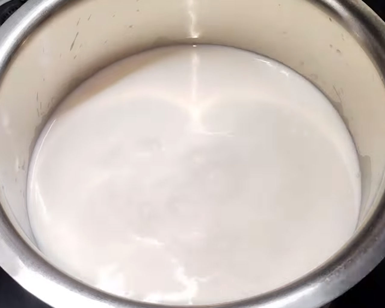 Boiling full cream milk in a large heavy-bottomed pot for chenna