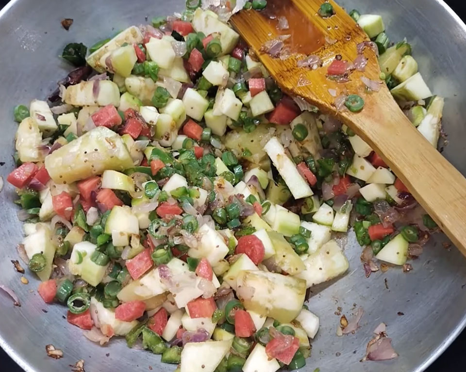 Chopped vegetables like brinjal, beans, carrot, capsicum, and pumpkin being sautéed in tadka for traditional sambar