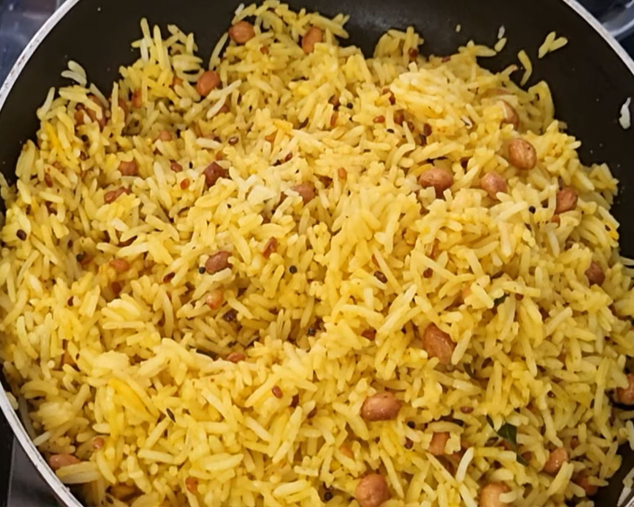 Yellow turmeric rice being mixed and cooked with lid