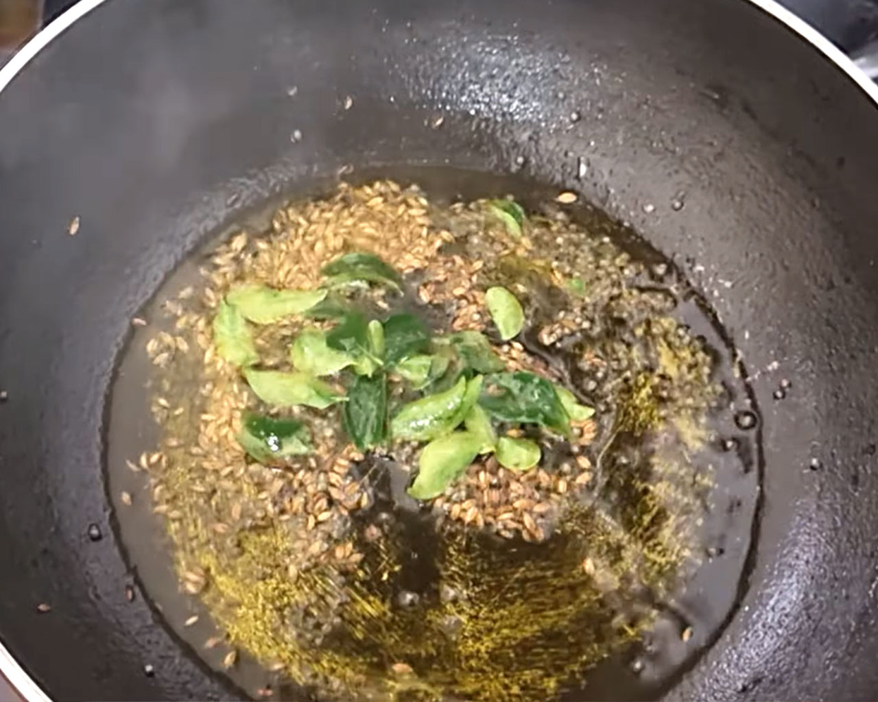 Fresh curry leaves being sautéed in oil