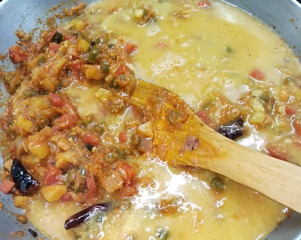 Cooked dal combined with tamarind pulp, jaggery, vegetables, simmering to make South Indian sambar