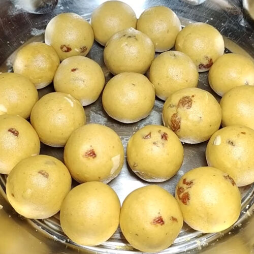 Plate of golden brown besan ladoos with dry fruits – easy Indian sweet recipe made with gram flour, ghee, and jaggery