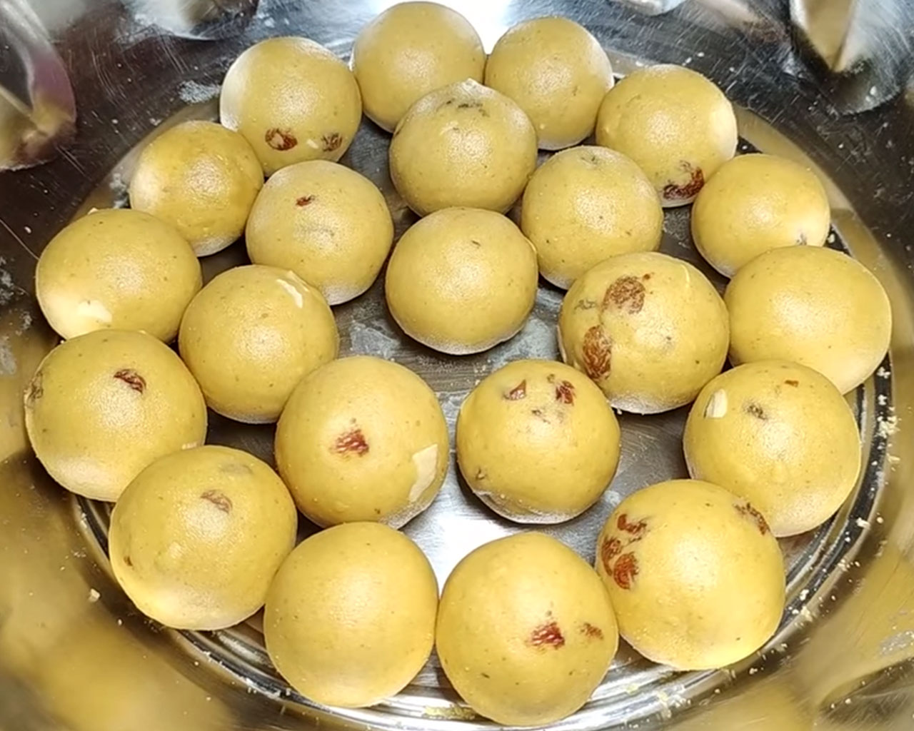 Plate of golden brown besan ladoos with dry fruits – easy Indian sweet recipe made with gram flour, ghee, and jaggery