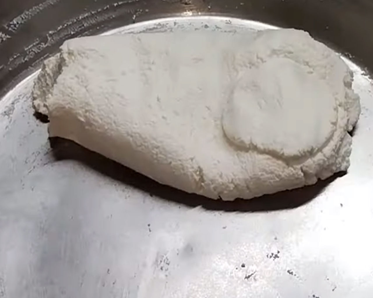 Kneading fresh chenna on a flat surface to make dough for soft rasgulla balls.
