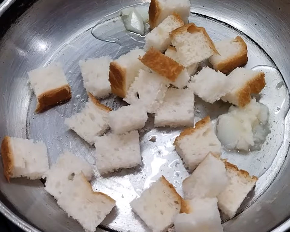 Frying bread cubes in ghee until golden brown for soup croutons.