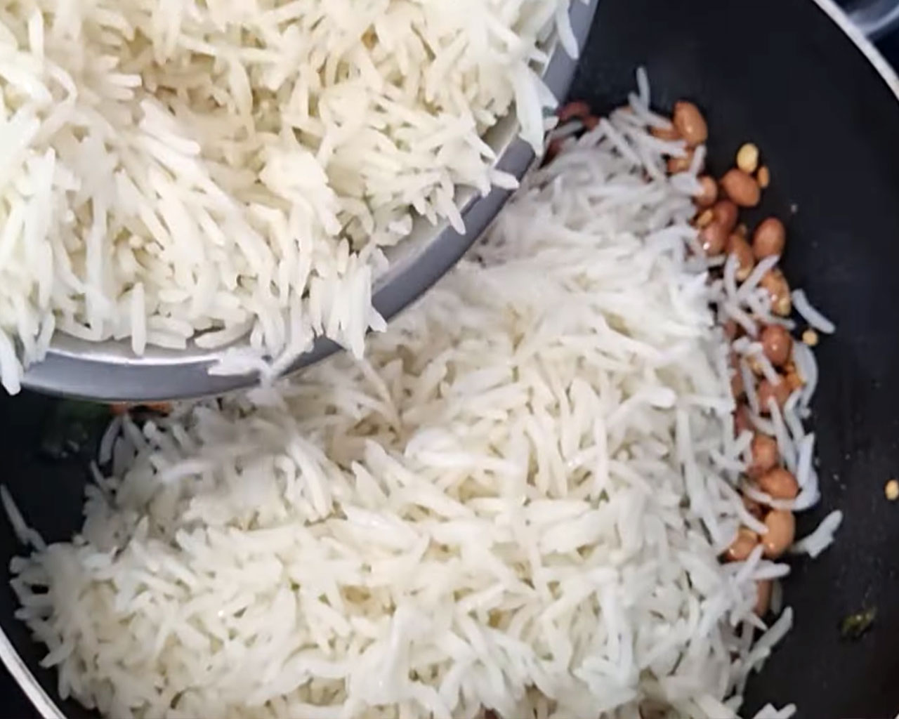 Boiled rice being added to roasted spices