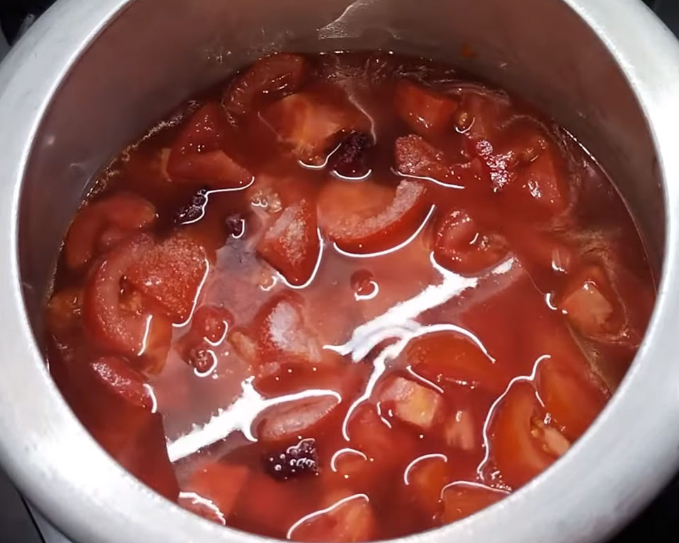 Pouring water and salt into the cooker with vegetables before pressure cooking tomato soup.