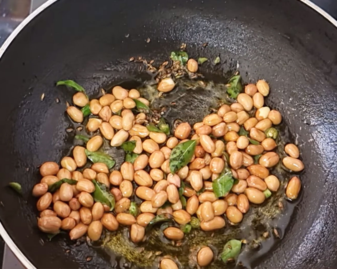 Raw peanuts being roasted for crunchy texture
