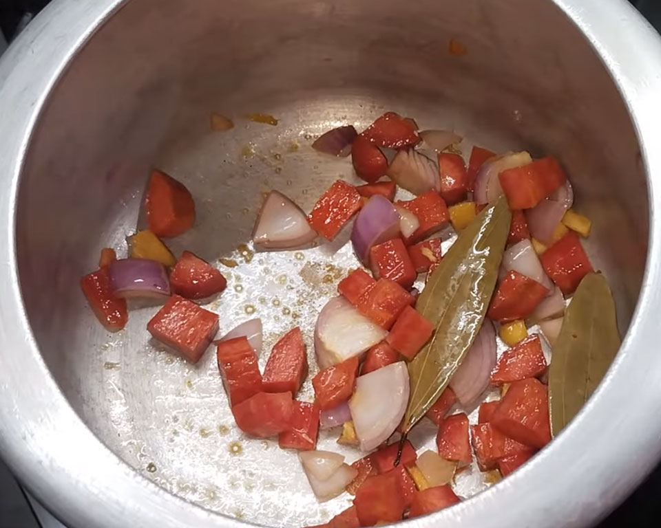 Cooking carrots, onions, and ginger in butter with bay leaves for tomato soup base