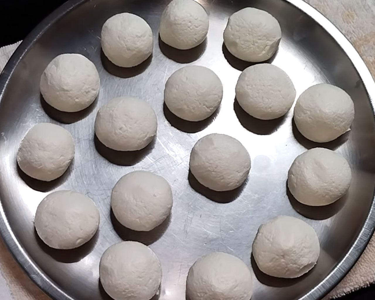 Rolling rasgulla dough into small smooth round balls between palms.