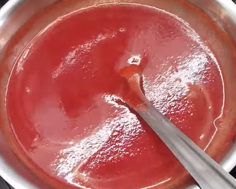 Simmering strained tomato soup in a pan with black pepper and sugar