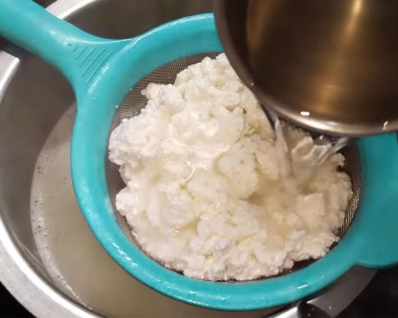 Straining curdled milk through sieve and rinsing chenna with cold water.