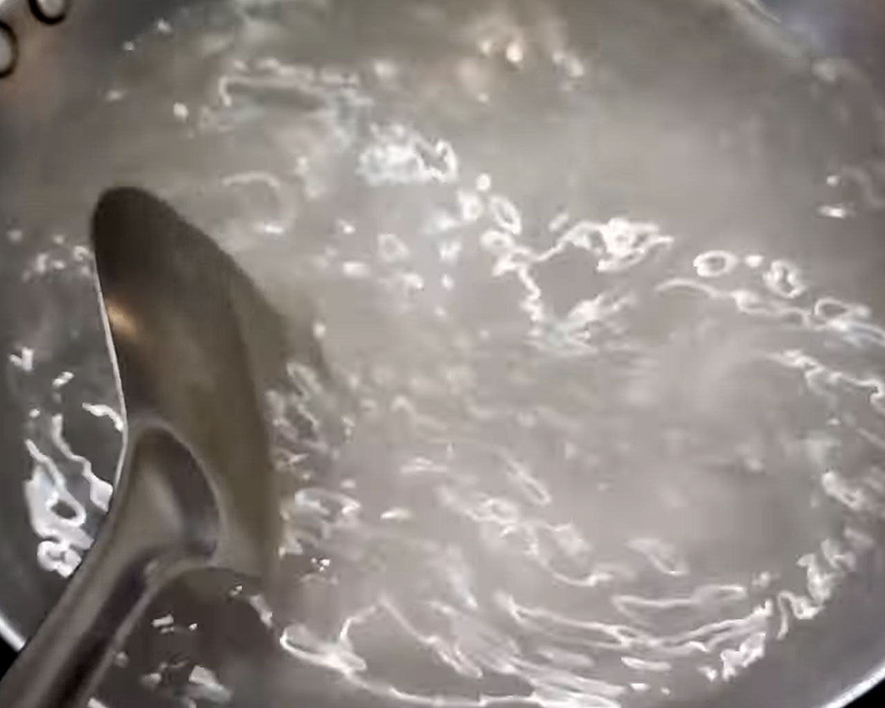 Boiling sugar syrup on high heat until it becomes slightly sticky for rasgulla.