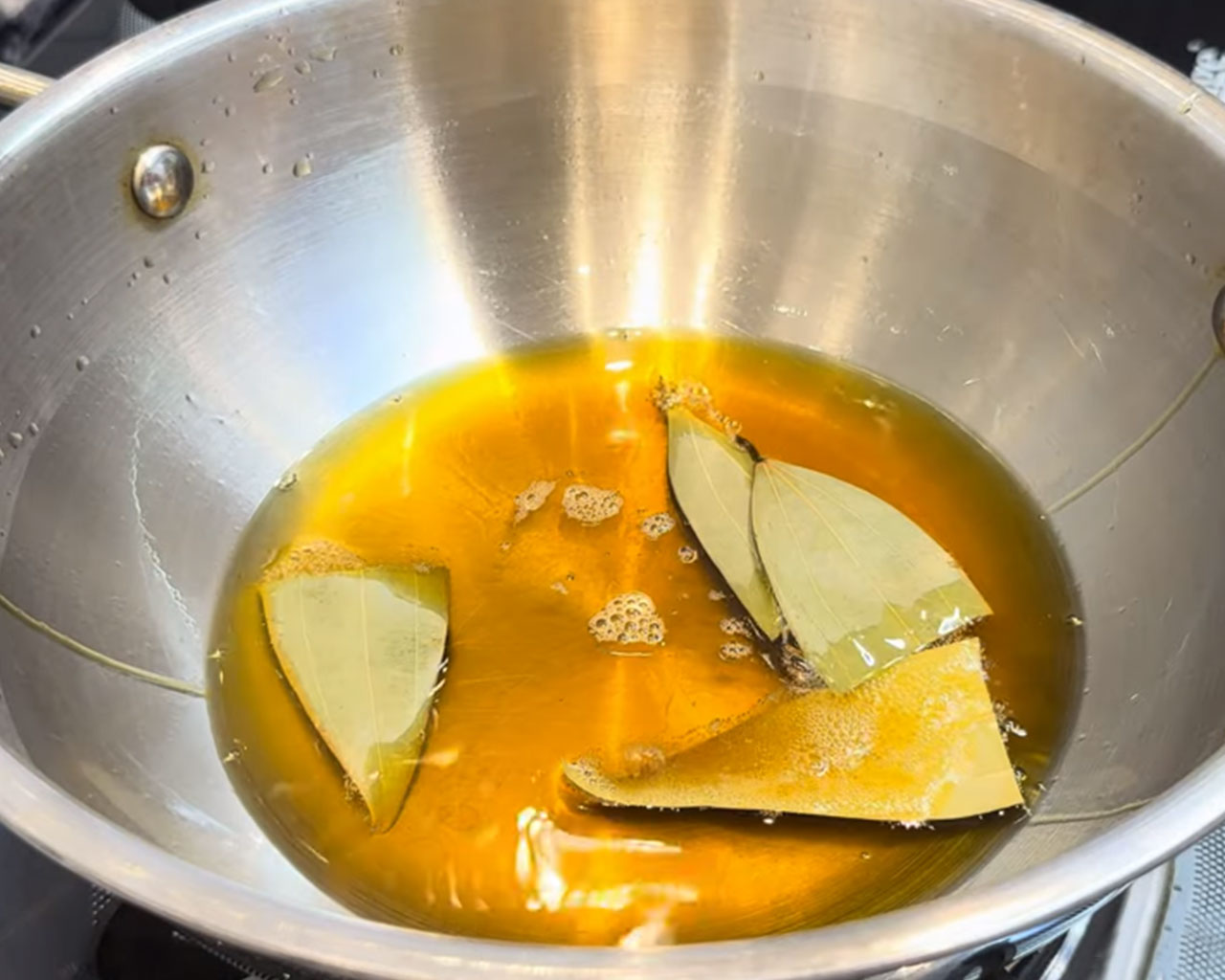 Bay leaves and whole spices sautéing in hot oil for making chicken curry