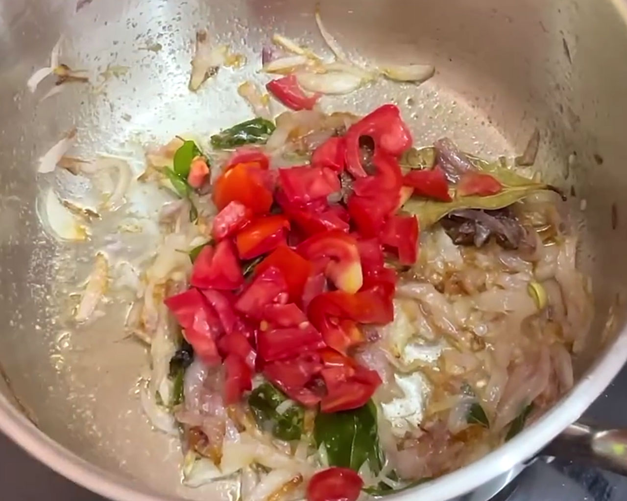 Chopped tomatoes being added to the sautéed onion base for making veg kurma gravy
