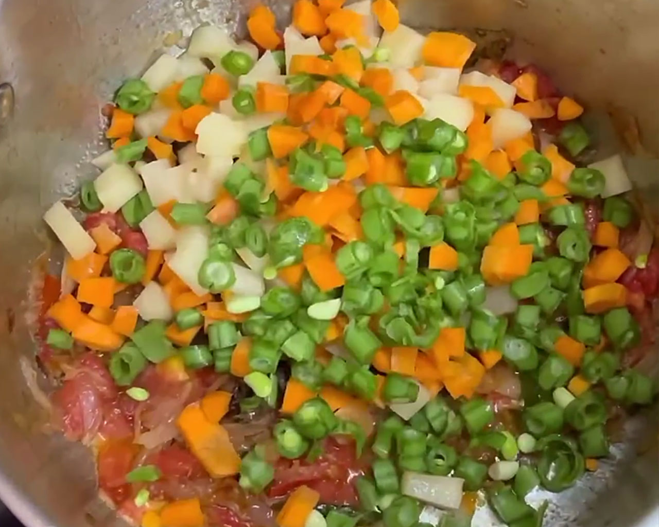 Diced potatoes, carrots, and green beans being added into the veg kurma curry base for veg kurma preparation.