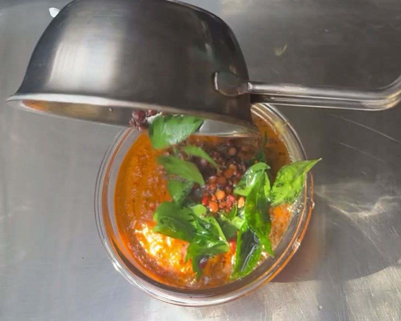 Final tadka being poured over freshly ground onion chutney