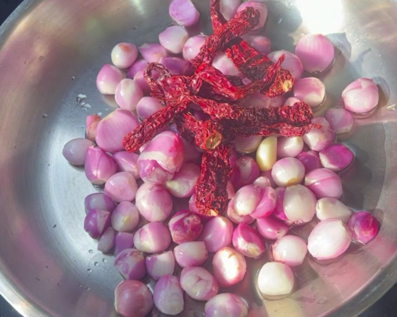 Adding dried red chilies to sautéed onions for a spicy chutney flavor.