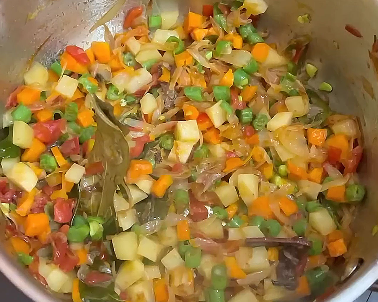 Diced potatoes, carrots, and green beans being mixed into the curry base for vegetable kurma preparation.