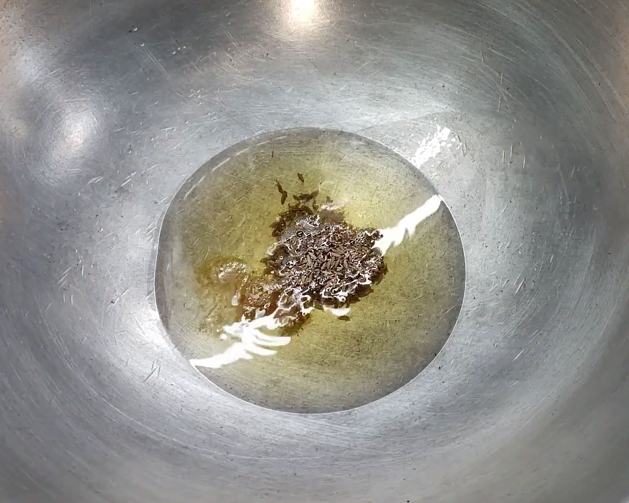 Cumin seeds and hing sizzling in hot oil for tamarind dipping sauce