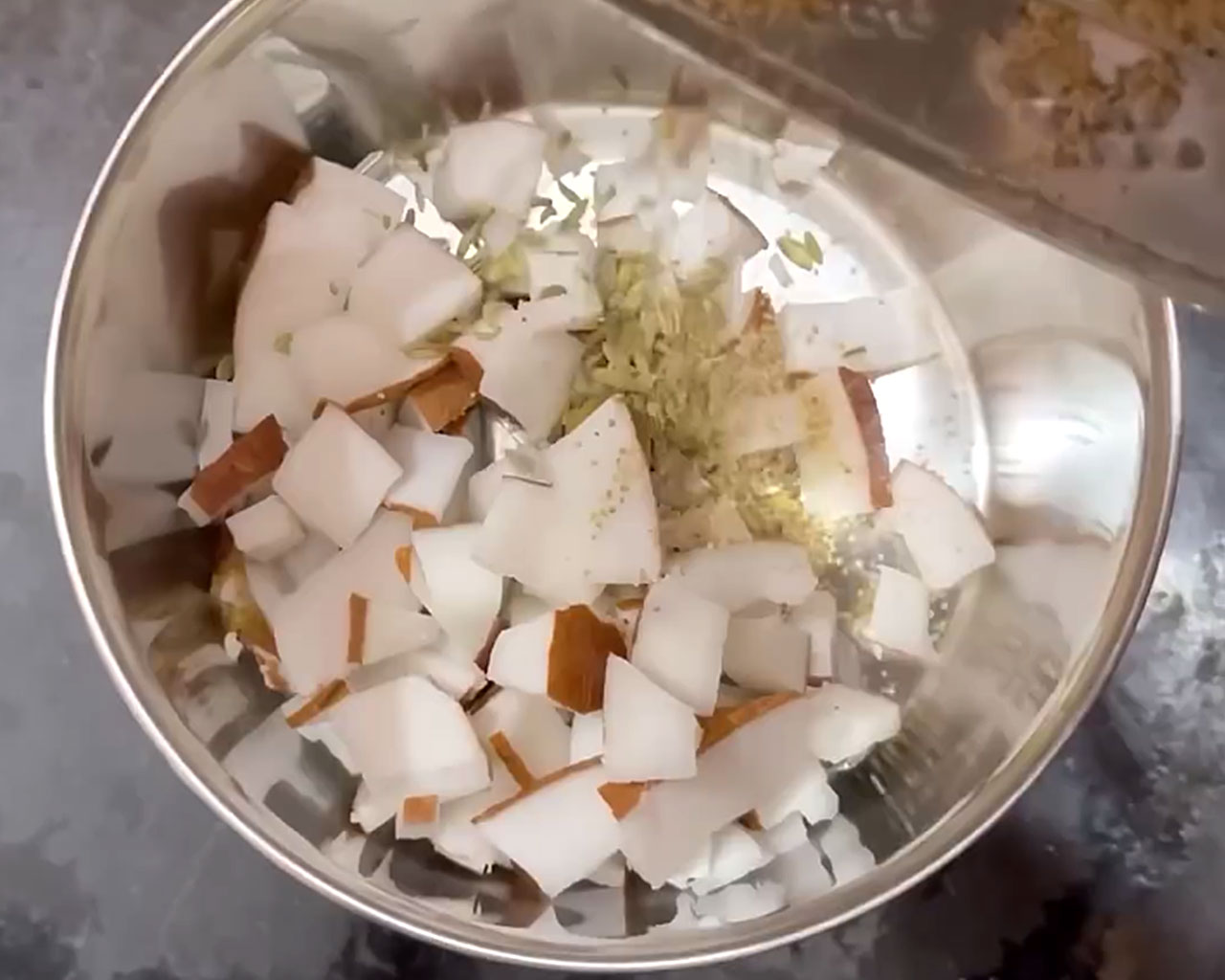 Coconut, fennel seeds, and carom seeds in a grinder jar being made into a coconut paste for South Indian kurma