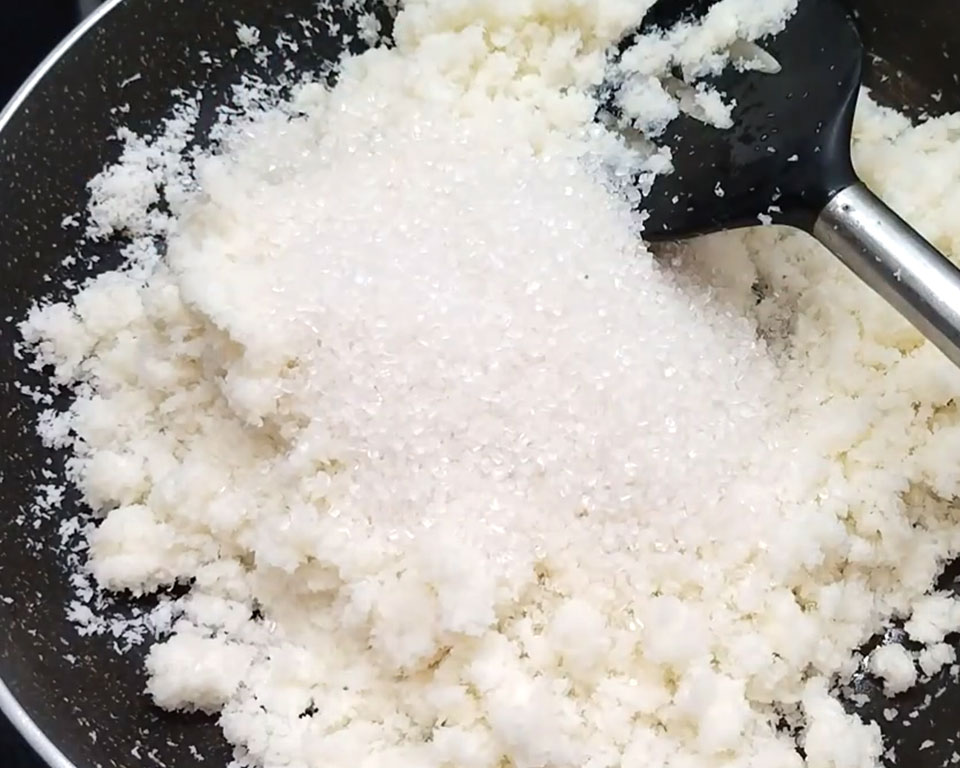 Adding sugar to coconut mixture and stirring