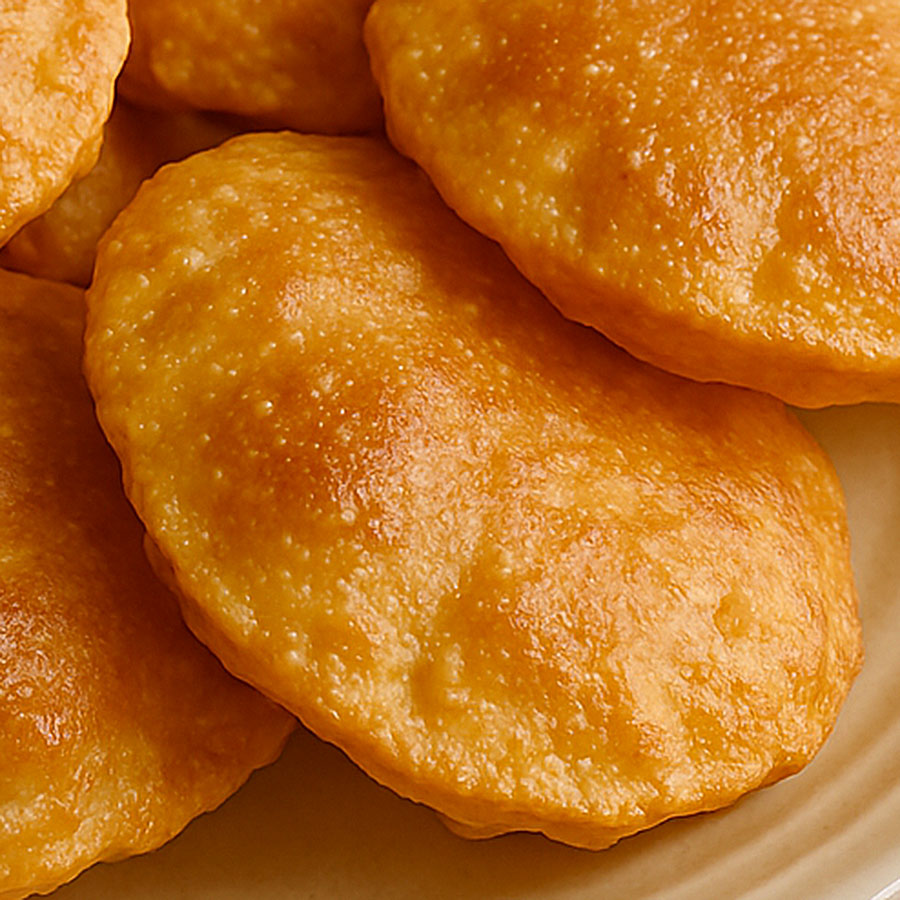 Removing fried puri from oil and placing it on a napkin to drain excess oil