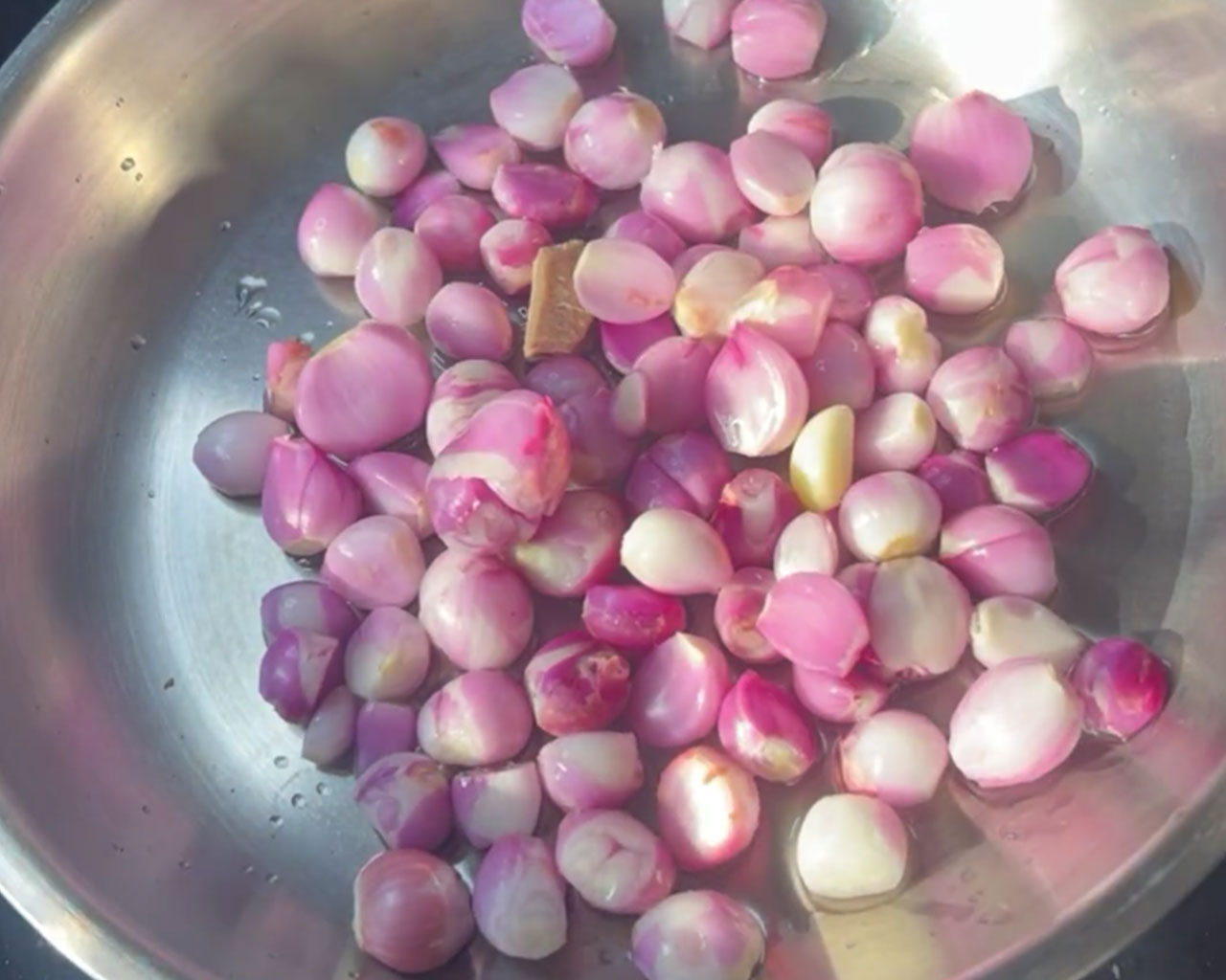 Baby onions being sautéed in oil until soft and golden for chutney