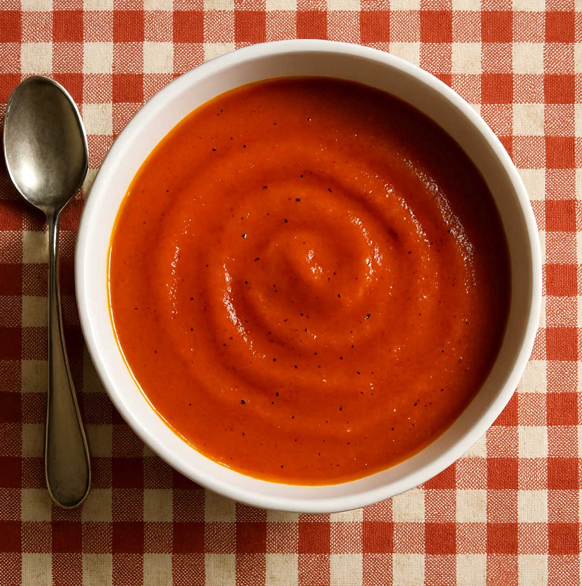Tomato soup served hot in a bowl, garnished with fresh basil and pepper.