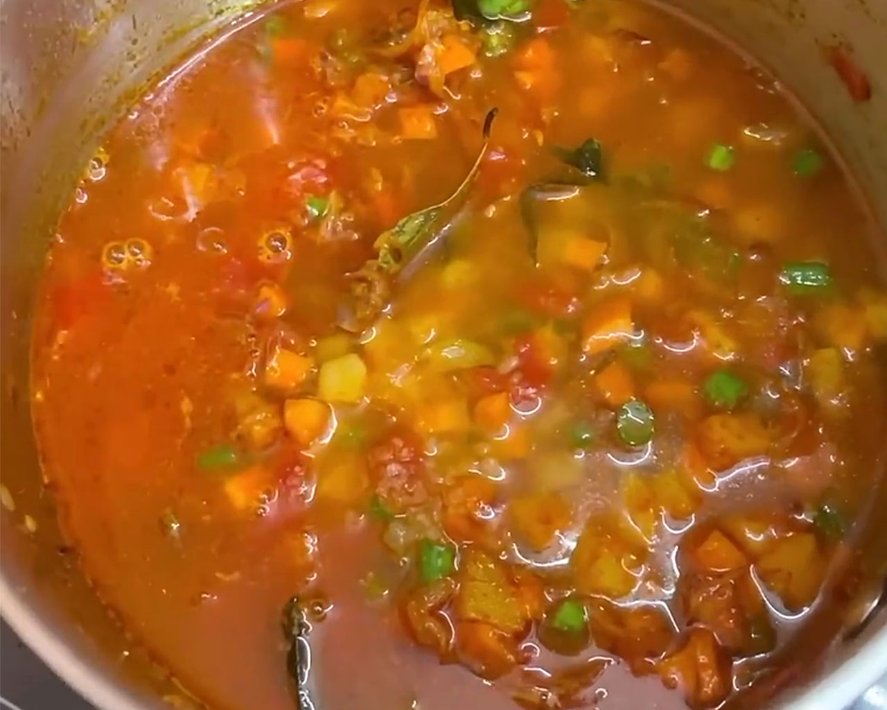 Simmering kurma in a pan after adding water and salt, with vegetables cooking in a mildly thick curry