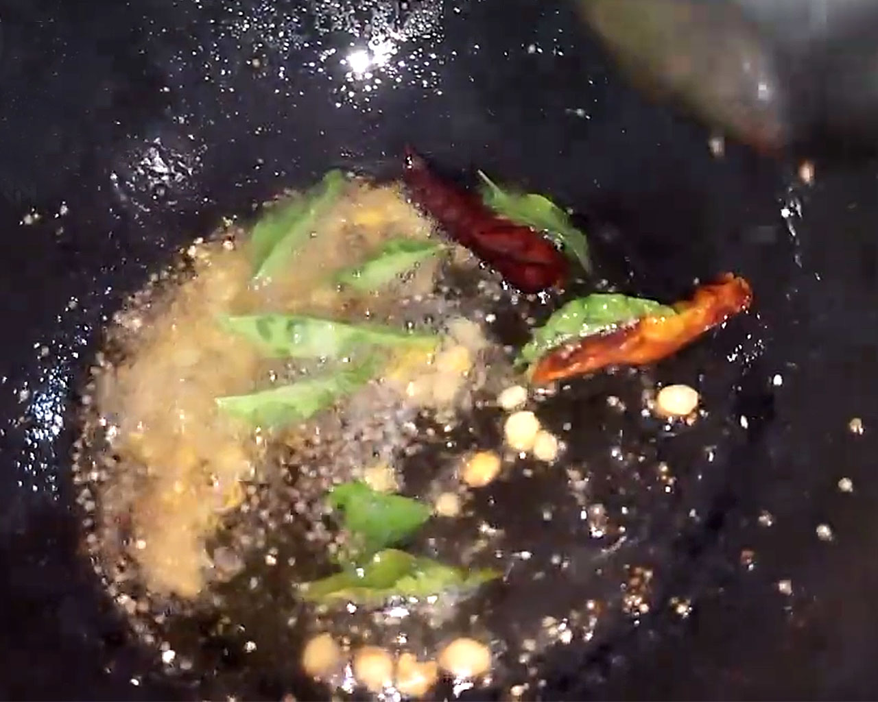Adding asafoetida (hing) and fresh curry leaves to tempering tadka