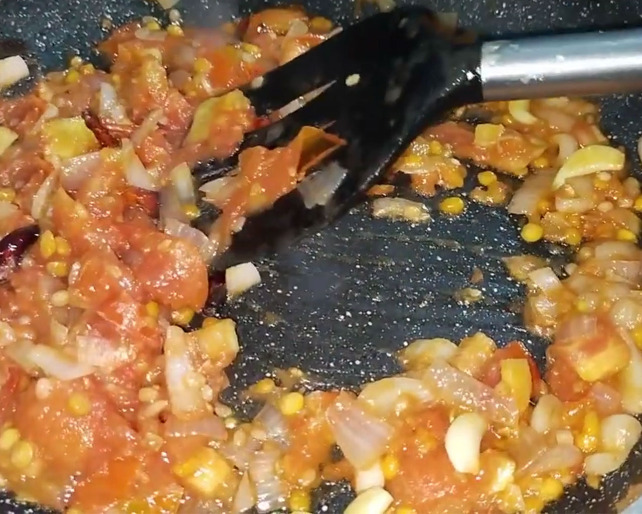 Mixing salt and red chili powder with tomatoes to soften them for chutney