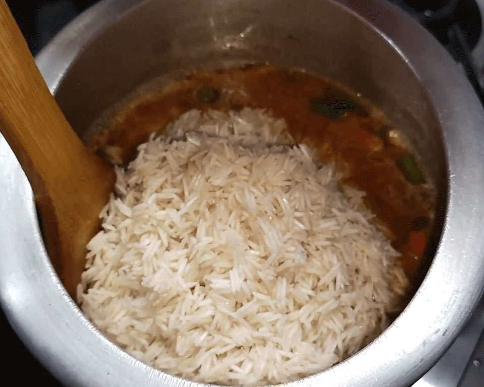 Soaked basmati rice and water added to spiced vegetable mixture
