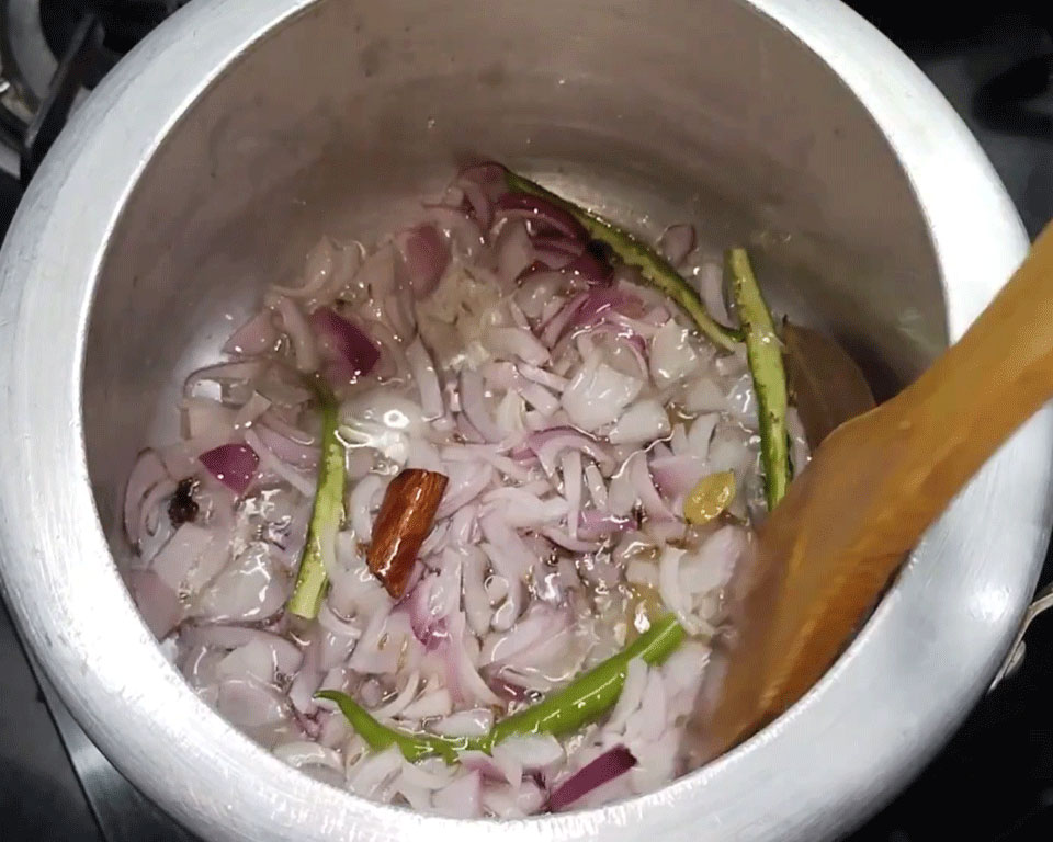 Finely chopped onions and slit green chilies frying until golden brown