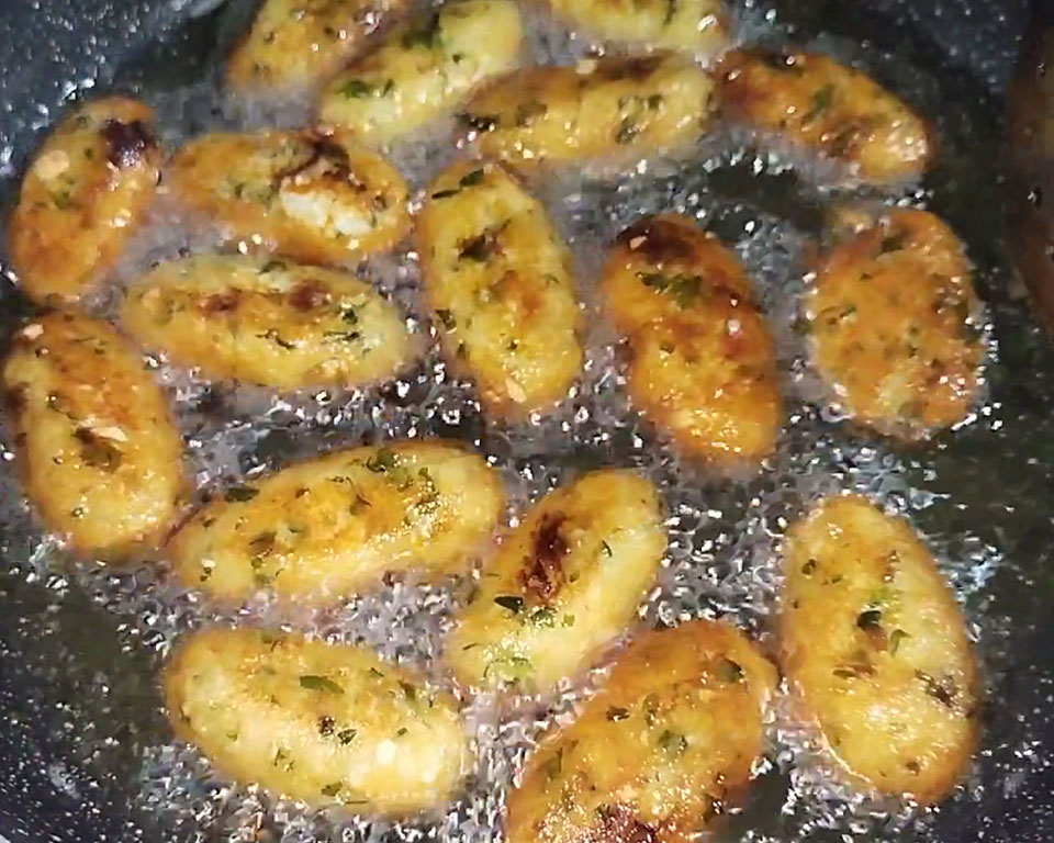 Golden brown fried paneer koftas drained on a paper towel.