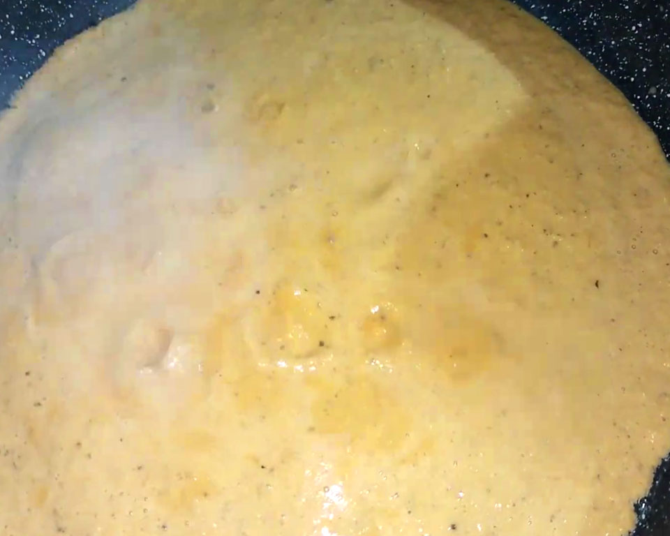 Simmering creamy blended malai kofta curry with fresh cream and garam masala in a pan.