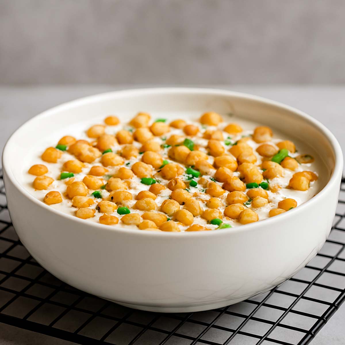 Indian boondi raita in a glass bowl, featuring soft yogurt mixed with crispy gram flour pearls, served as a refreshing side dish for Indian curries.