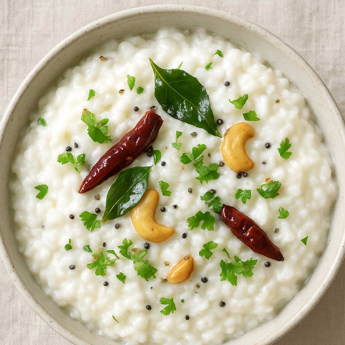 bowl of curd rice garnished with coriander and red chili