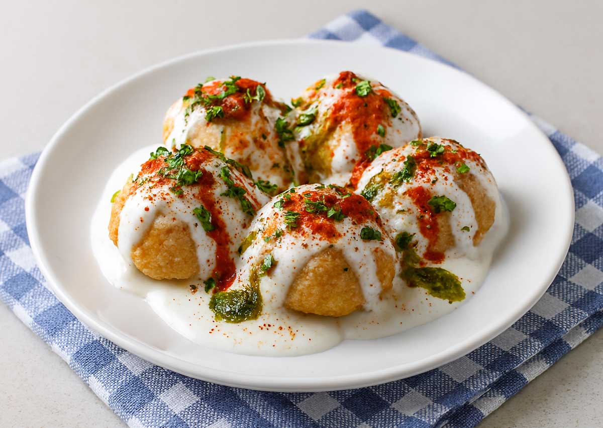 Plate of soft Dahi Vada with roasted cumin, chaat masala, and chili powder sprinkled on top of vada