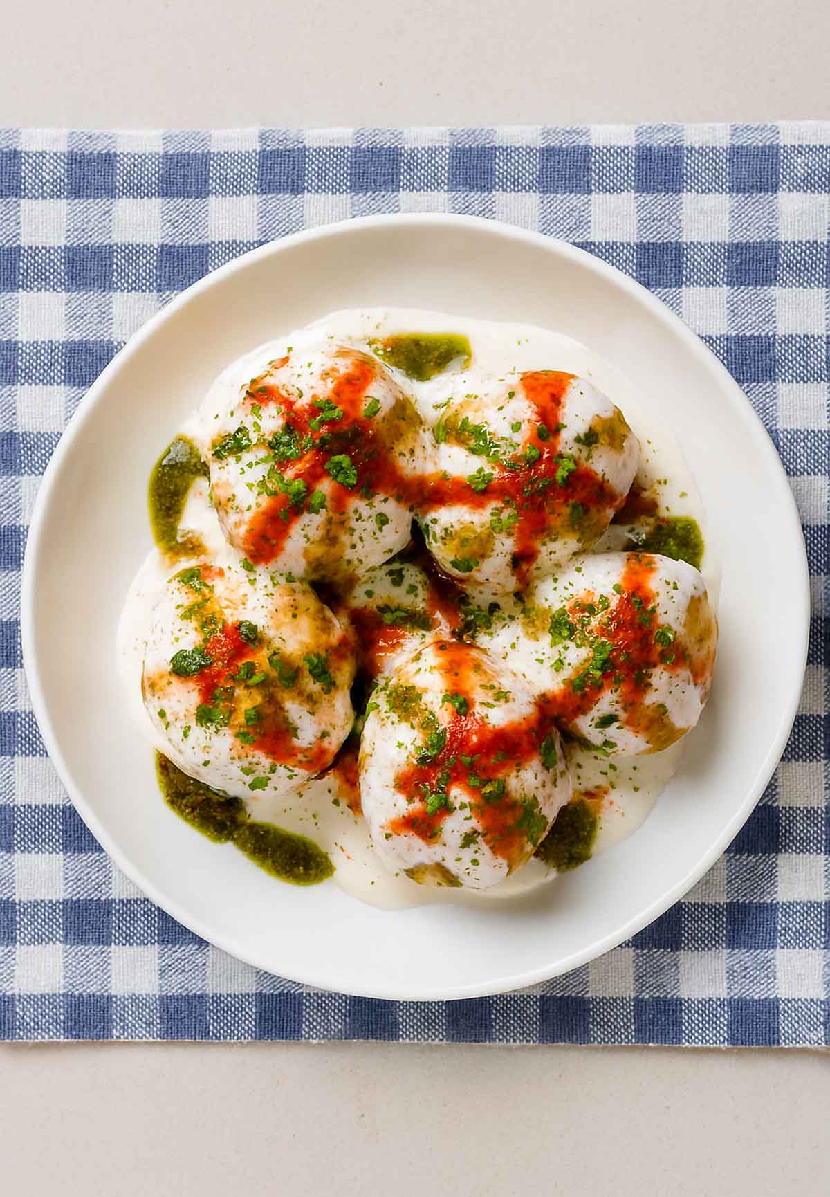 Dahi Vada topped with yogurt, tamarind chutney, and coriander.