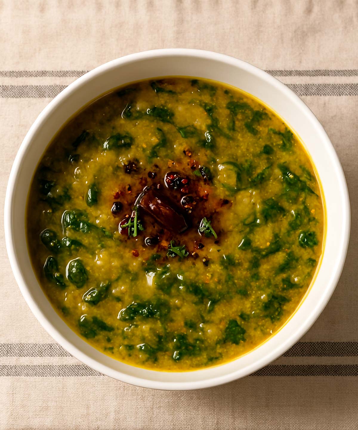 Indian lentil curry, dal pakak with fresh spinach leaves, served hot in a bowl.